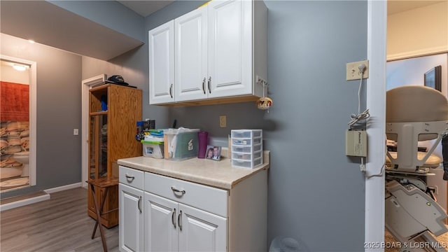 kitchen featuring light countertops, white cabinets, light wood-style flooring, and baseboards