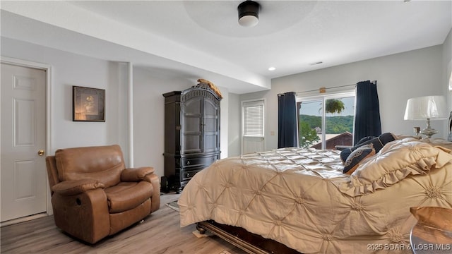 bedroom with access to outside and wood finished floors