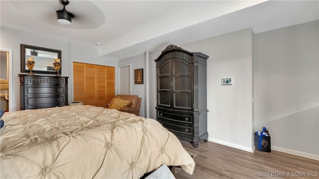 bedroom featuring ceiling fan, a closet, wood finished floors, and baseboards