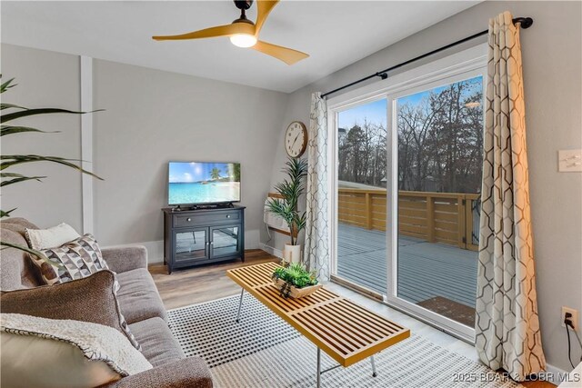 living room featuring ceiling fan, wood finished floors, and baseboards