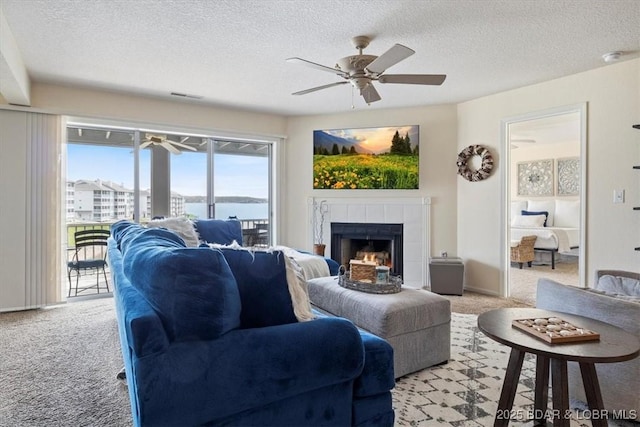 488 Regatta Bay Dr Unit 2C, Lake Ozark, MO 65049 - living room featuring light colored carpet, a ceiling fan, a tile fireplace, and a textured ceiling