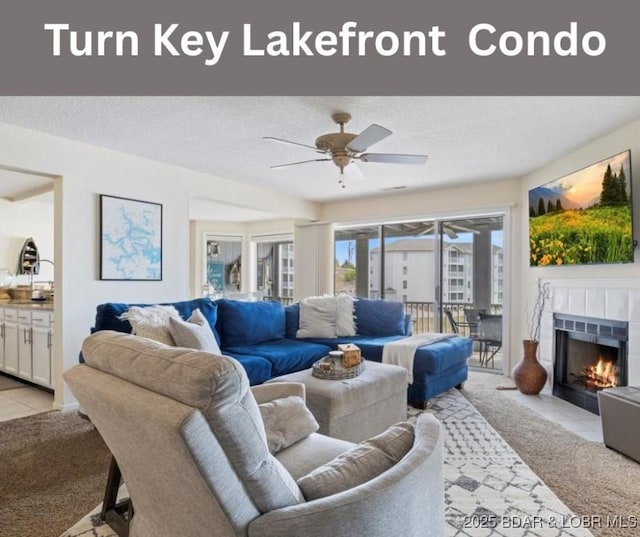 488 Regatta Bay Dr Unit 2C, Lake Ozark, MO 65049 - living room with light colored carpet, a ceiling fan, a tiled fireplace, and a textured ceiling