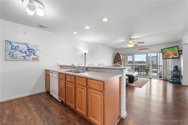 kitchen with a sink, dark wood-style floors, a peninsula, light countertops, and dishwasher