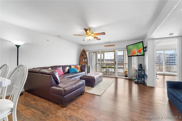 living area with visible vents, a ceiling fan, and wood finished floors