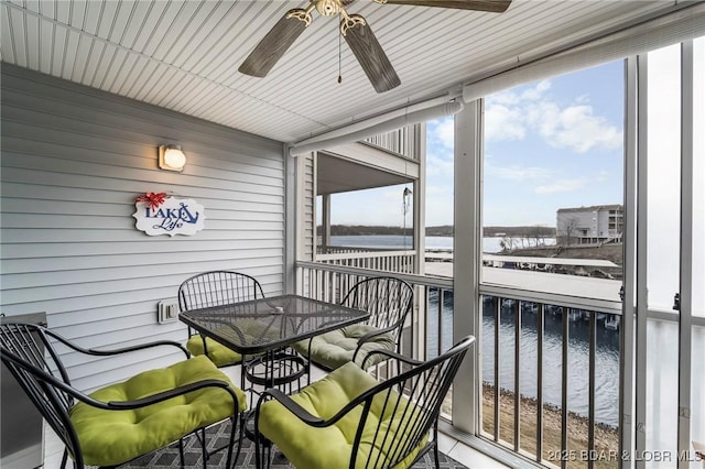 sunroom with a ceiling fan and a water view