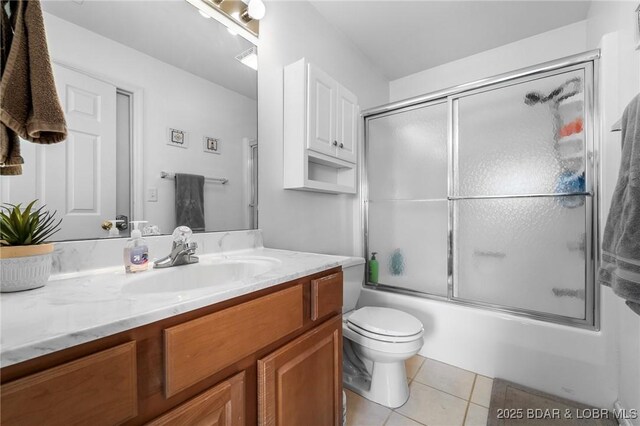 bathroom with tile patterned flooring, toilet, vanity, and enclosed tub / shower combo