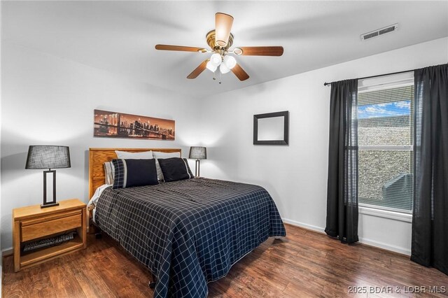 bedroom featuring visible vents, a ceiling fan, baseboards, and wood finished floors