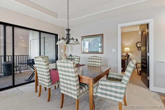 dining area with a tray ceiling, carpet flooring, baseboards, and an inviting chandelier