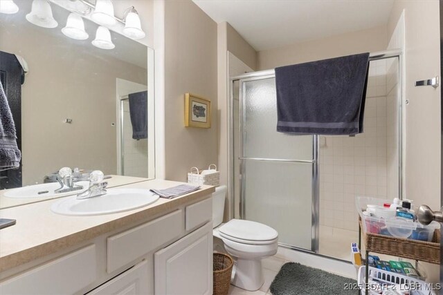 bathroom featuring toilet, a stall shower, vanity, and tile patterned floors