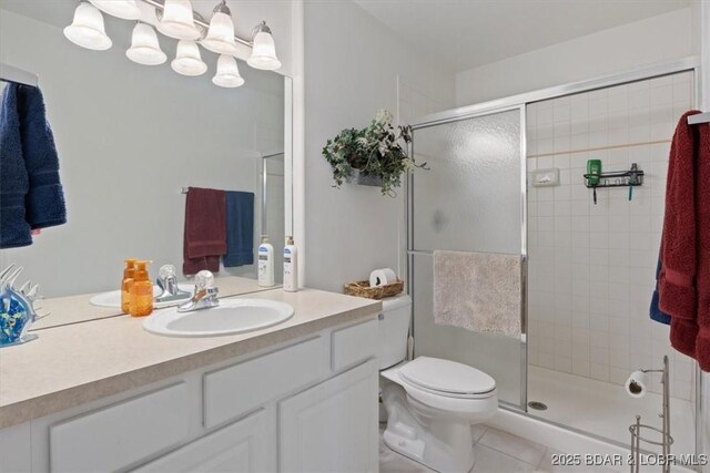 bathroom with a stall shower, vanity, toilet, and tile patterned floors