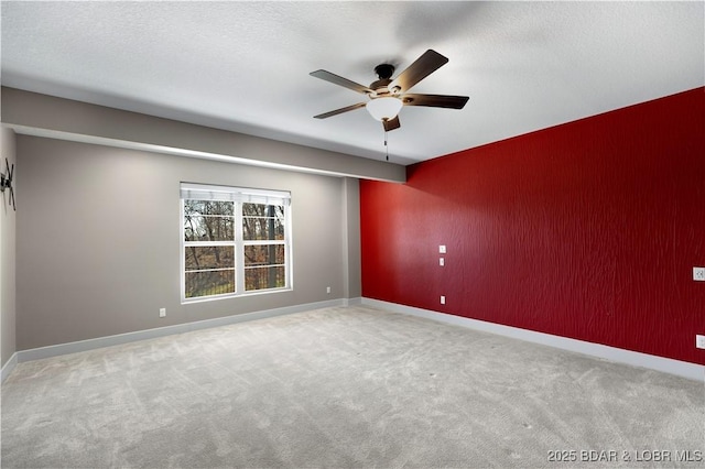 spare room with baseboards, carpet floors, ceiling fan, a textured ceiling, and an accent wall