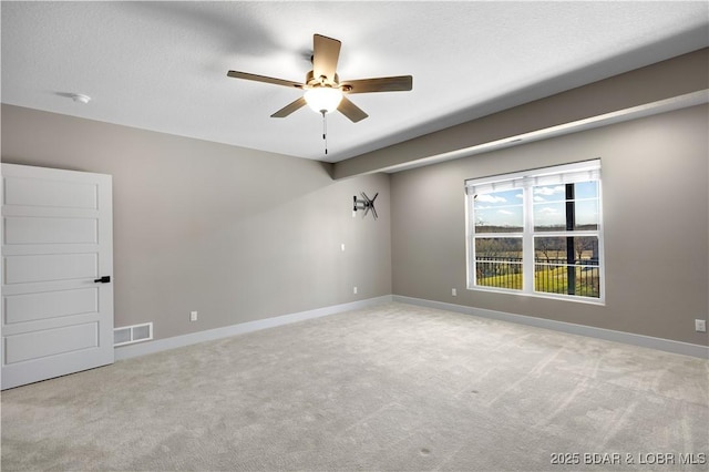 carpeted empty room with visible vents, a textured ceiling, a ceiling fan, and baseboards