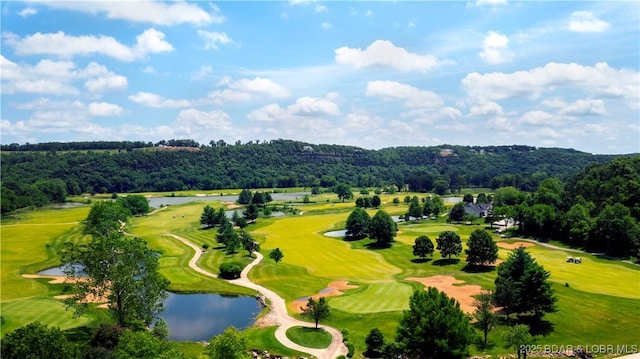 aerial view featuring a wooded view, golf course view, and a water view