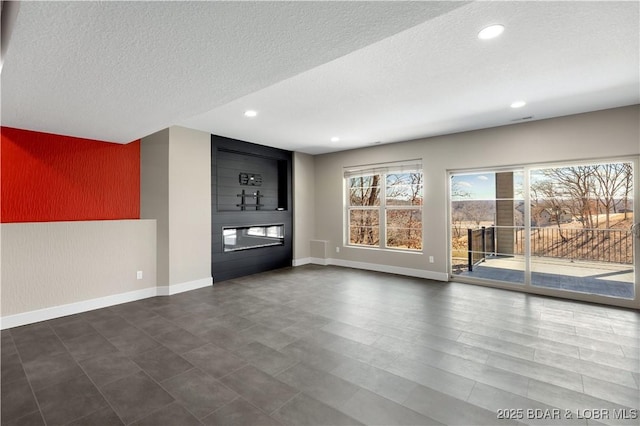 unfurnished living room with recessed lighting, a fireplace, baseboards, and a textured ceiling