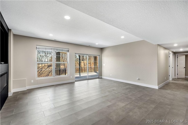 unfurnished living room with a glass covered fireplace, recessed lighting, baseboards, and a textured ceiling