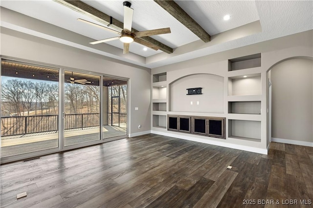 unfurnished living room with built in shelves, baseboards, beamed ceiling, wood finished floors, and a ceiling fan