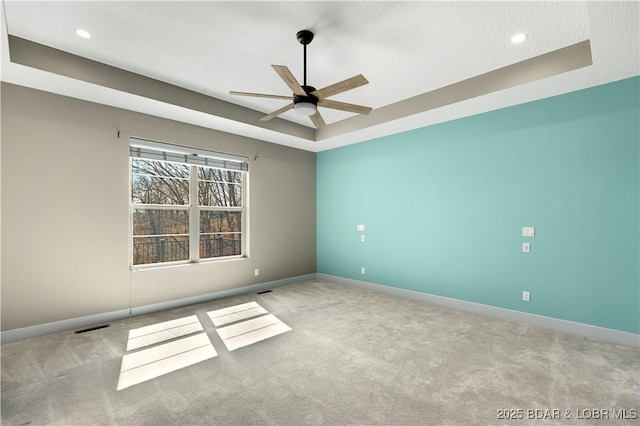 empty room featuring carpet flooring, baseboards, a raised ceiling, and visible vents