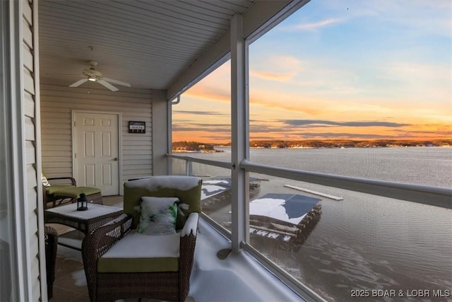 balcony at dusk featuring ceiling fan and a water view