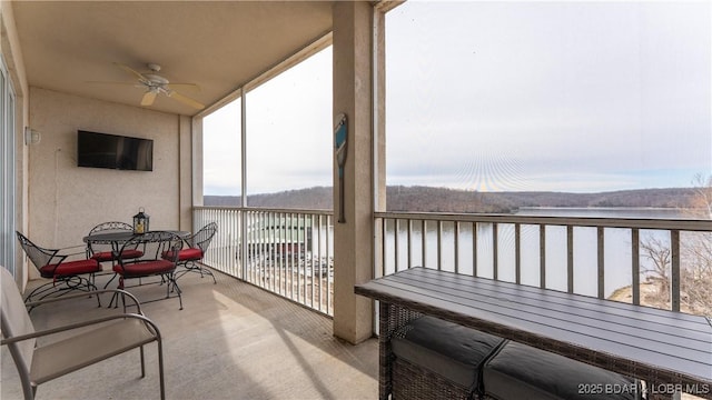 sunroom featuring a water view and a ceiling fan