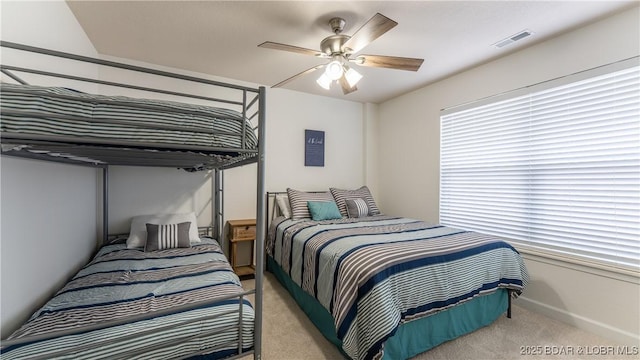 bedroom featuring a ceiling fan, visible vents, and light colored carpet