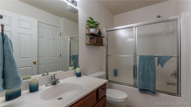 bathroom with toilet, shower / bath combination with glass door, and vanity