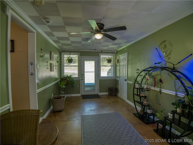 interior space with baseboards, a ceiling fan, concrete flooring, and crown molding