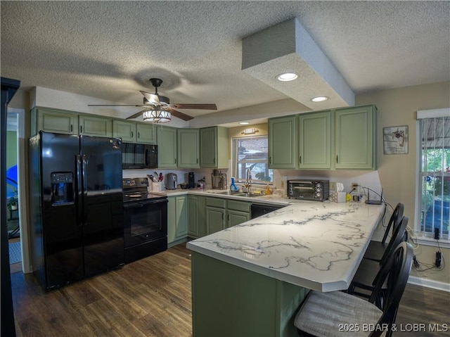 kitchen featuring black appliances, a peninsula, light countertops, and green cabinetry