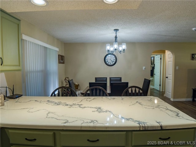 kitchen featuring a textured ceiling, arched walkways, pendant lighting, and green cabinetry