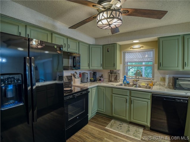 kitchen featuring black appliances, green cabinets, a sink, and light countertops