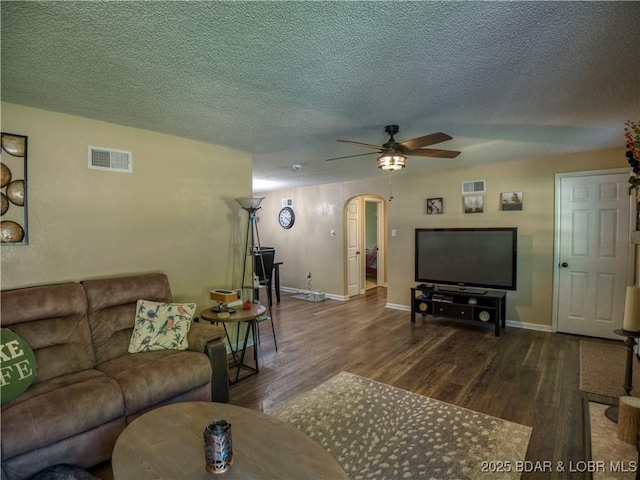 living room with arched walkways, visible vents, ceiling fan, wood finished floors, and baseboards