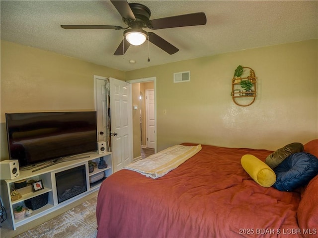 bedroom featuring a textured ceiling, ceiling fan, and visible vents