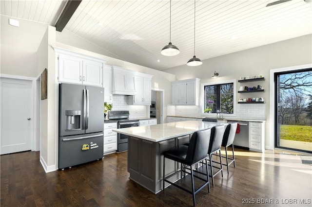 kitchen featuring lofted ceiling with beams, tasteful backsplash, premium range hood, and appliances with stainless steel finishes