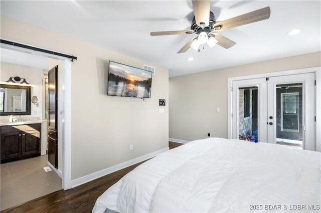 bedroom featuring wood finished floors, baseboards, visible vents, a barn door, and access to outside