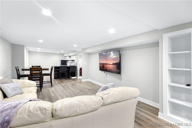 living area featuring recessed lighting, baseboards, built in shelves, and wood finished floors