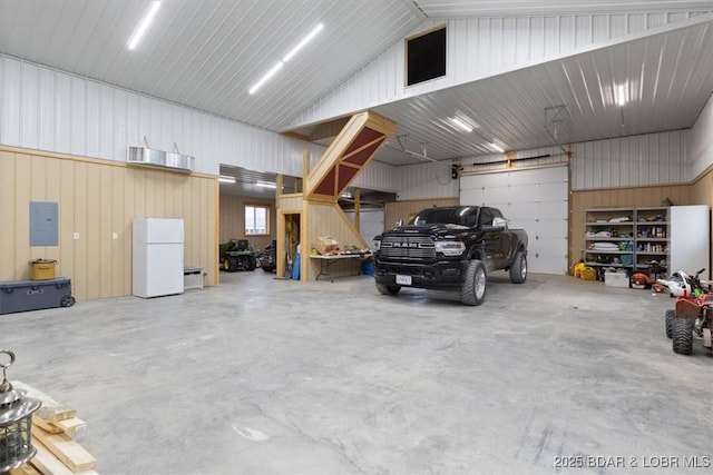 garage with electric panel, metal wall, and freestanding refrigerator