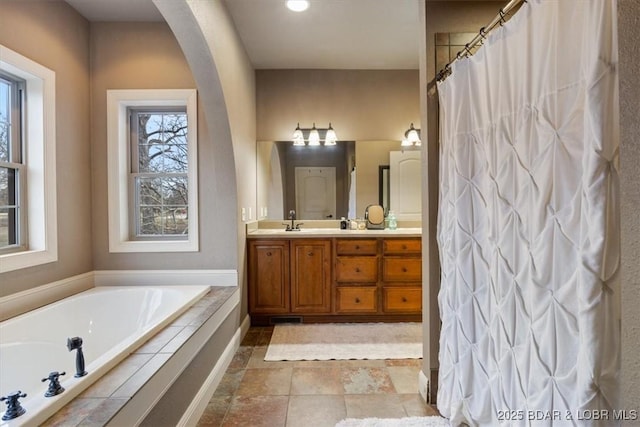 bathroom featuring double vanity, a sink, and a bath