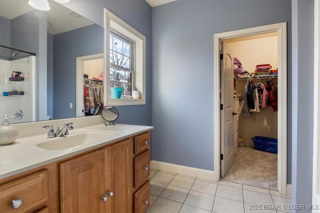 full bath with tile patterned flooring, vanity, baseboards, a shower, and a walk in closet