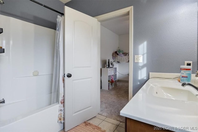 bathroom featuring a textured wall, vanity, shower / bath combo with shower curtain, and tile patterned floors