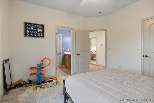 bedroom with light colored carpet, ceiling fan, visible vents, and ensuite bathroom