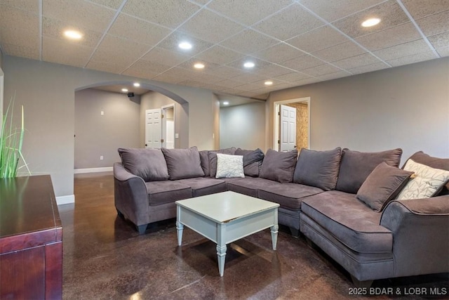 living room with arched walkways, a drop ceiling, recessed lighting, and baseboards