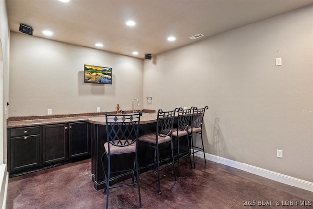 interior space featuring recessed lighting, visible vents, baseboards, finished concrete flooring, and wet bar