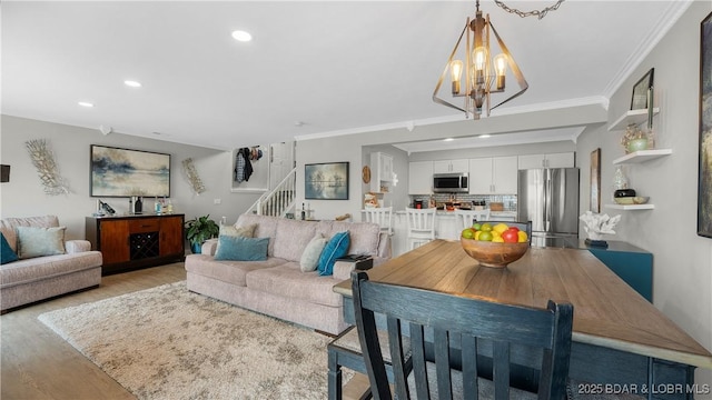 living room featuring ornamental molding, recessed lighting, stairway, an inviting chandelier, and light wood finished floors