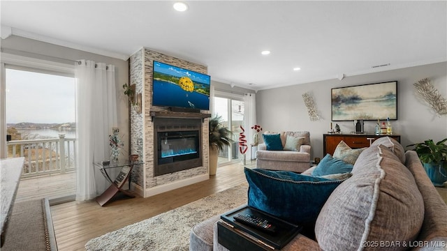 living area with recessed lighting, a fireplace, wood finished floors, and crown molding