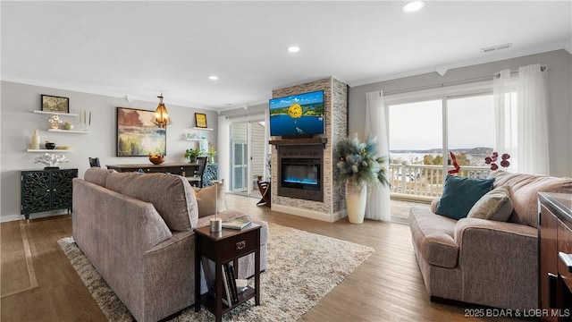 living area with visible vents, recessed lighting, a fireplace, and wood finished floors