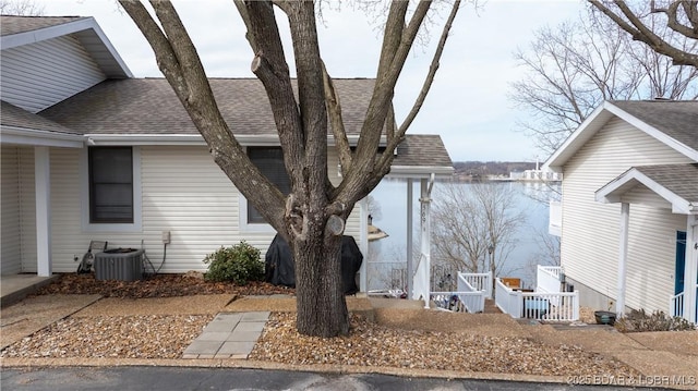 view of property exterior with central AC unit and roof with shingles