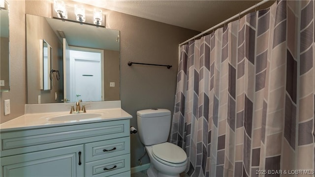 bathroom with a textured wall, a shower with shower curtain, vanity, and toilet