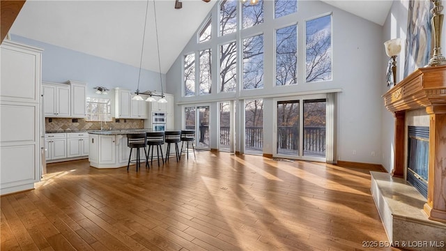 kitchen with dark countertops, light wood-style floors, a high end fireplace, open floor plan, and a kitchen breakfast bar