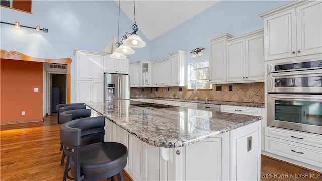 kitchen featuring stone countertops, a kitchen island, appliances with stainless steel finishes, and decorative backsplash