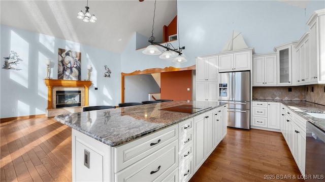 kitchen featuring stainless steel appliances, a glass covered fireplace, a kitchen island, and dark wood-style floors