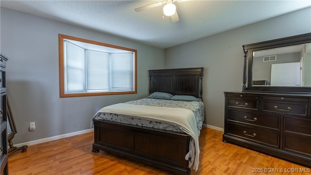 bedroom with light wood-style flooring, visible vents, baseboards, and ceiling fan